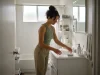 Bathroom Storage Ideas for Small Spaces That Actually Last Bathroom storage ideas for small spaces — woman organizing bathroom counter with clear bins and a tray system