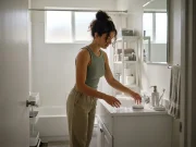 Bathroom Storage Ideas for Small Spaces That Actually Last Bathroom storage ideas for small spaces — woman organizing bathroom counter with clear bins and a tray system