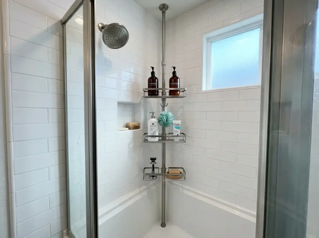 Tension pole shower caddy with adjustable wire shelves holding shampoo and body wash in tiled shower