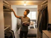 Why Budget Closet Makeovers Always Revert Woman organizing reach-in closet on a budget, clothes sorted in piles on bed nearby