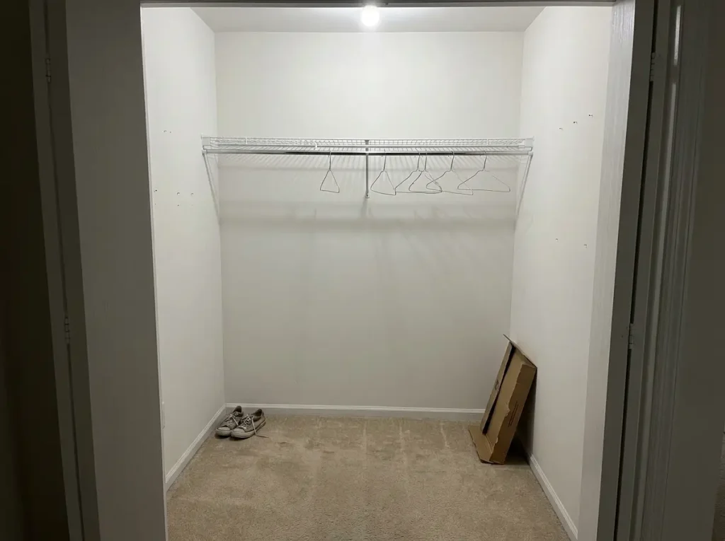 Empty reach-in closet showing wasted space below single rod and unused floor zone