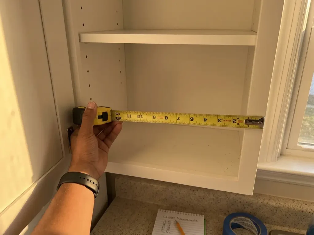 tape measure across kitchen cabinet shelf showing 12 inch depth measurement