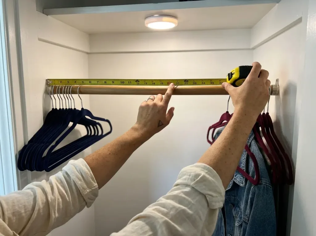 Hands measuring center point of shared closet rod to mark equal division between two sides