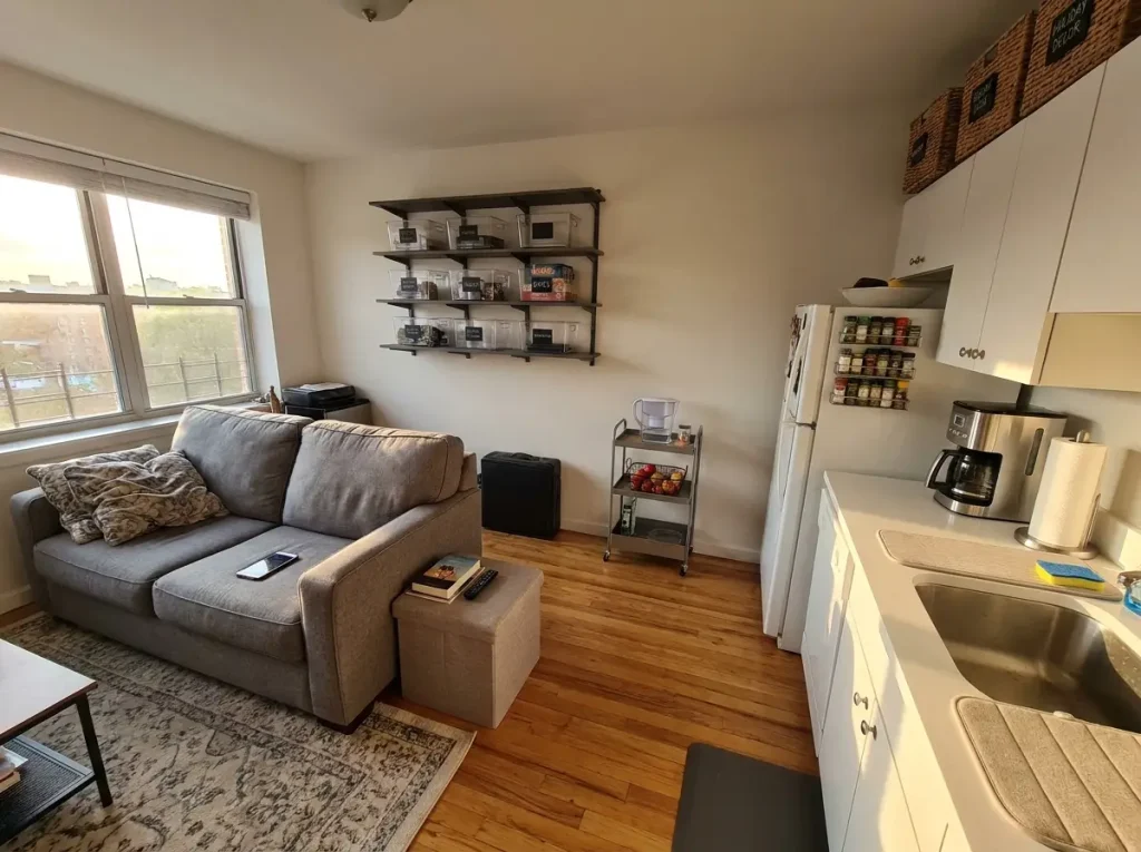 Small organized apartment living room and kitchen showing clean surfaces and labeled storage three months after organizing