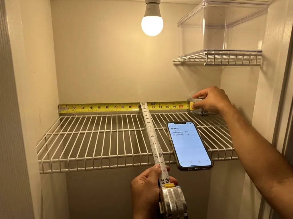 Tape measure showing shelf depth and width inside a small pantry closet