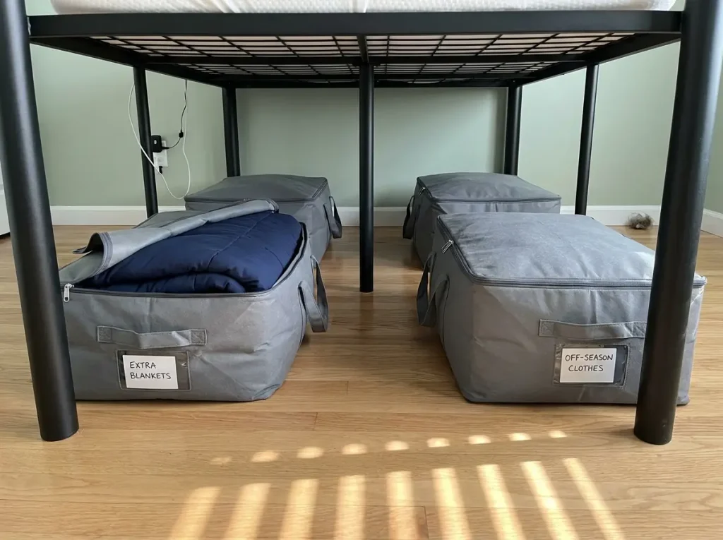 Four labeled Amazon Basics fabric storage bags organized under metal bed frame with 10 inches of clearance showing capacity