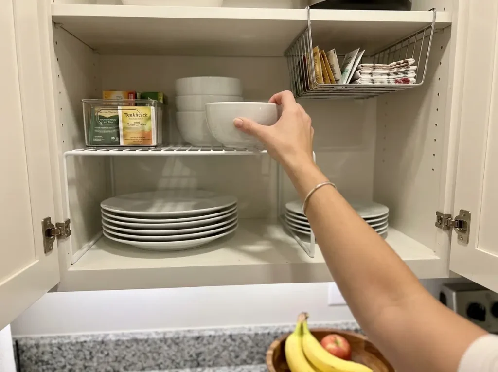 Upper kitchen cabinet with shelf riser doubling storage space for plates and bowls
