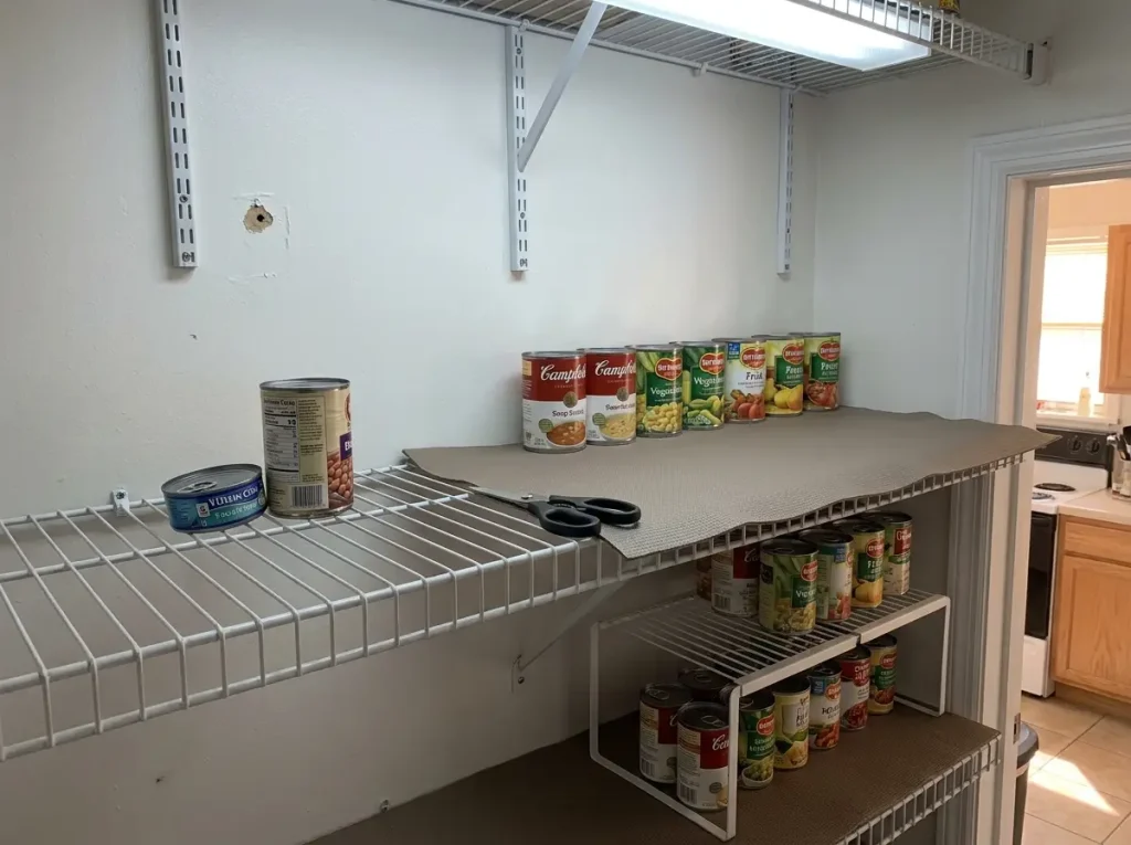 Shelf liner installed on wire pantry shelf with canned goods stable and organized