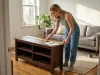 5 TV Stands with Storage Worth Buying and 2 to Skip Woman comparing TV stand measurements in a small living room before buying
