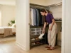 How to Organize Shoes in a Closet That Won’t Pile Up Again Woman organizing shoes in a reach-in closet with a slim rack and clear stackable boxes