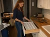 Best Kitchen Drawer Organizers That Hold Their Size Woman lowering a white madesmart expandable utensil tray into an open kitchen drawer at dusk