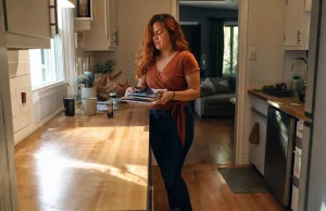 How to Declutter Kitchen Counters for Good Woman mid-way through decluttering a kitchen counter, clearing items into a sorting pile