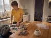 Junk Drawer Organization Ideas for Stuff With No Home Woman sorting an emptied junk drawer into piles on a kitchen counter before organizing it