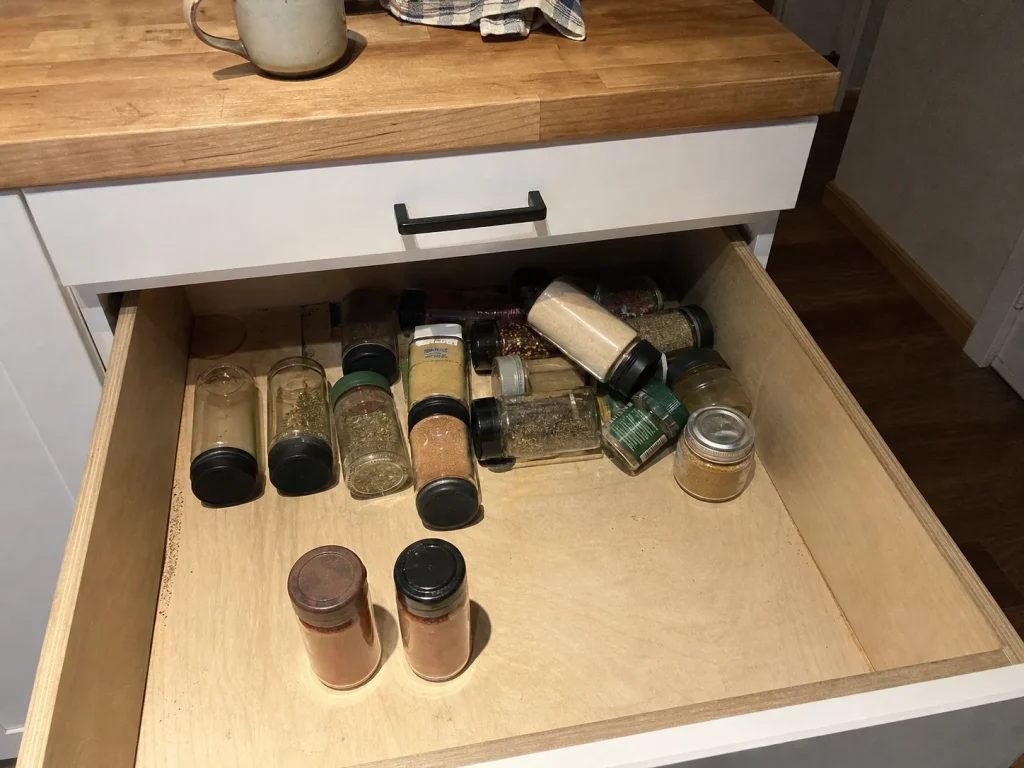 Spice Drawer Organization That Stops Jars From Rolling 1 Open spice drawer with jars slid into a diagonal pile at the back and two duplicate jars in front