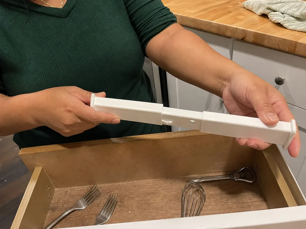 Best Kitchen Drawer Organizers That Hold Their Size 1 Hands showing a collapsed spring-loaded drawer divider that no longer holds its expanded width