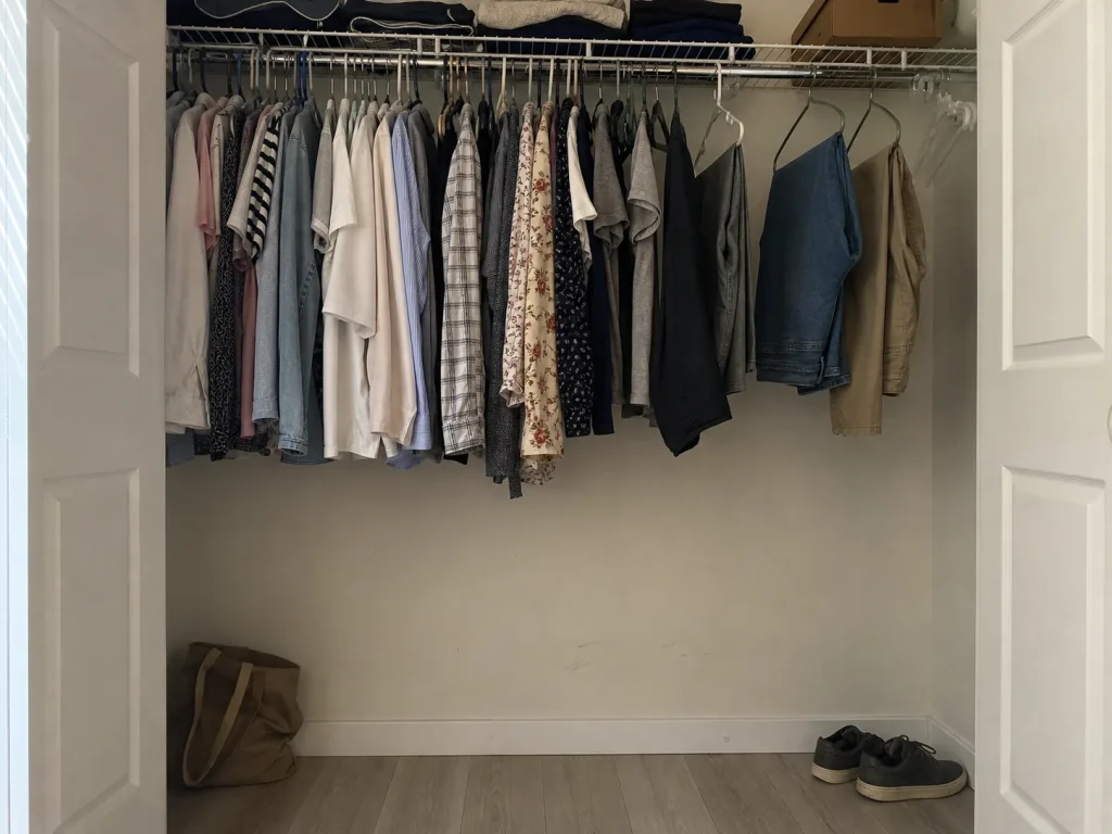 Single closet rod hung high with dead empty space below short hanging shirts