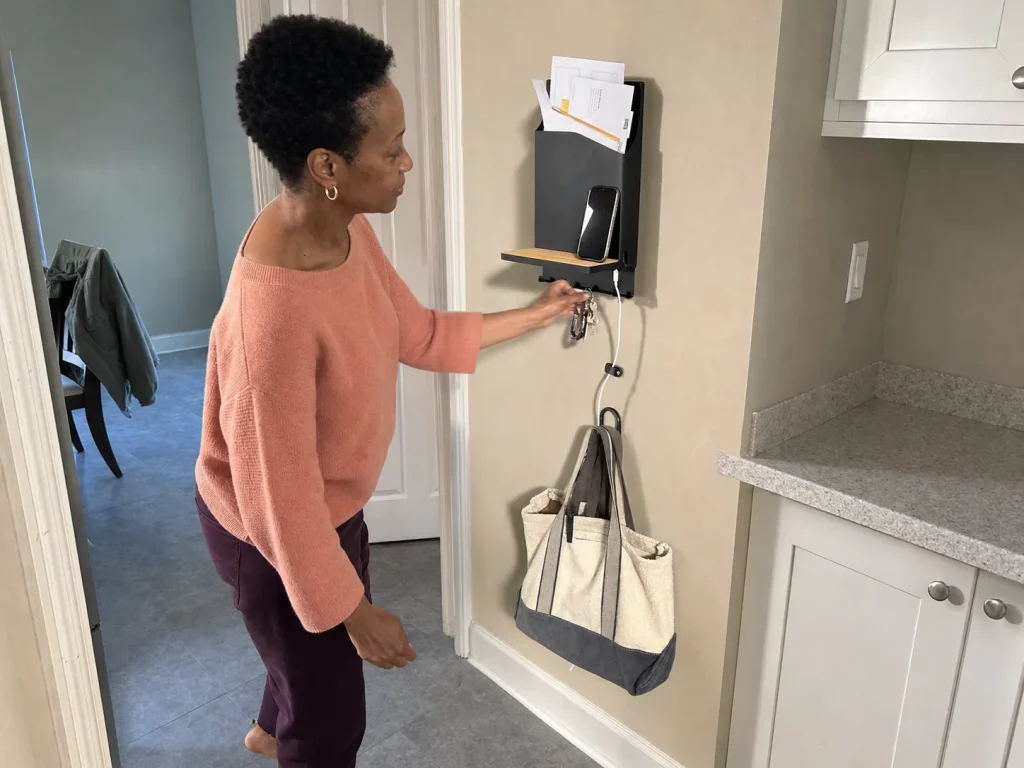 Woman hanging keys on a wall-mounted drop zone with mail slot near the kitchen to stop counter clutter