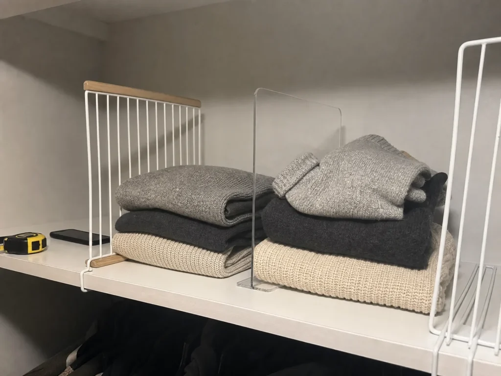 Wood, clear acrylic and coated-wire shelf dividers lined up on a closet shelf for comparison