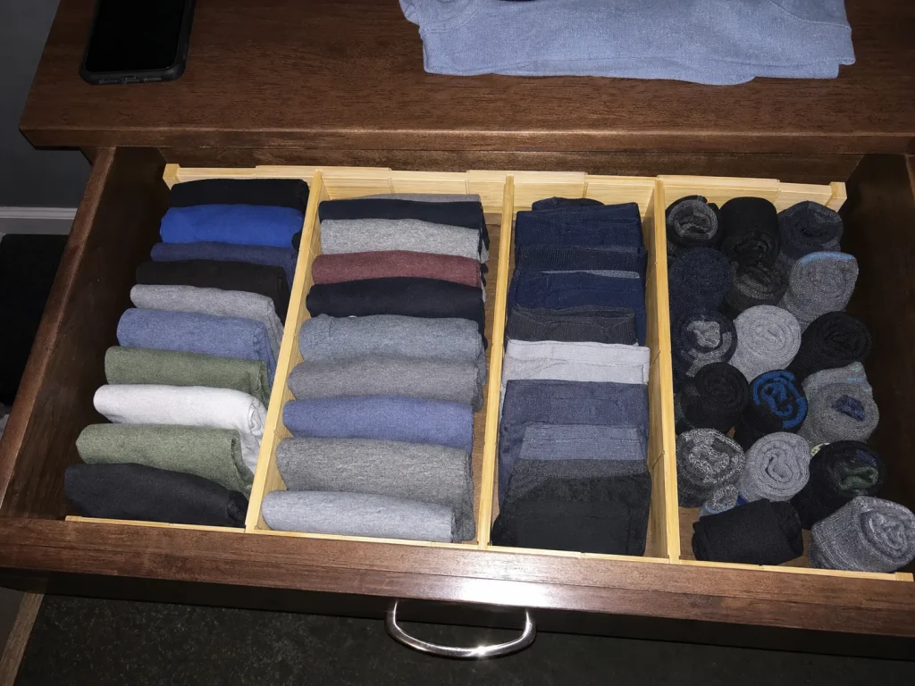 Wide dresser drawer split into lanes by adjustable bamboo dividers holding folded clothes