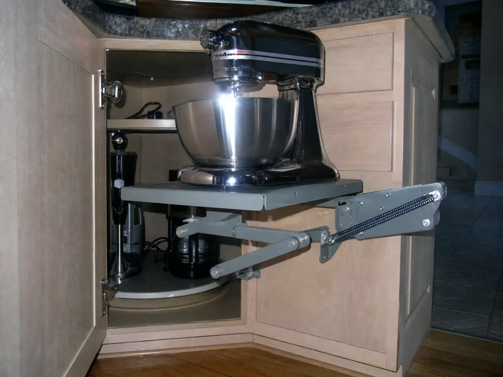 Base cabinet appliance lift raising a stand mixer with a turntable in the corner cabinet behind