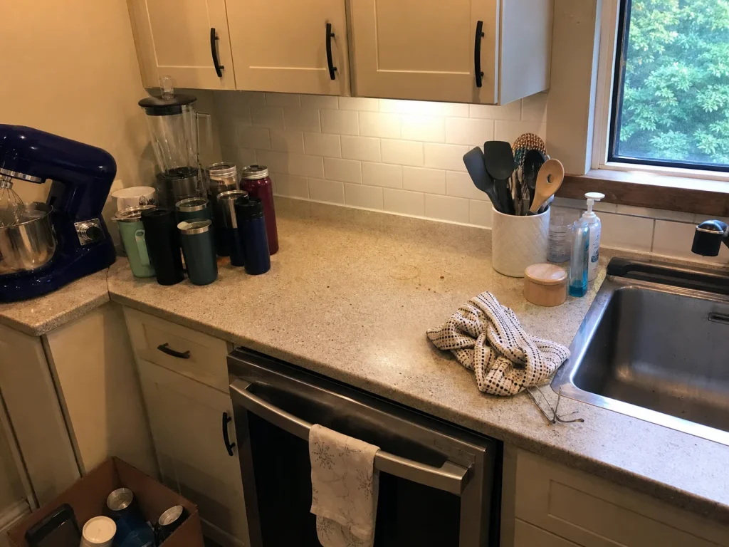 How to Organize Kitchen Counters That Stay Clear 4 Kitchen counter mid-declutter with items sorted into keep and relocate piles beside an empty bin
