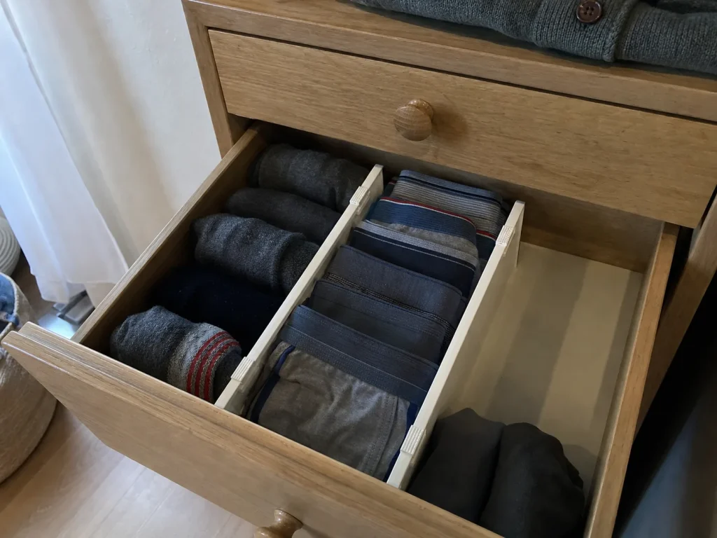 Narrow shallow dresser drawer with short plastic dividers separating folded socks and underwear