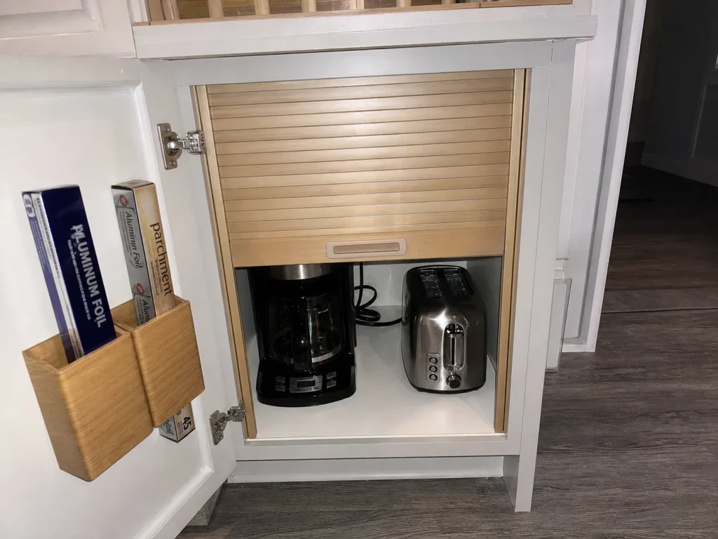 Open cabinet with a tambour appliance-garage door and over-door wrap organizer in a small kitchen