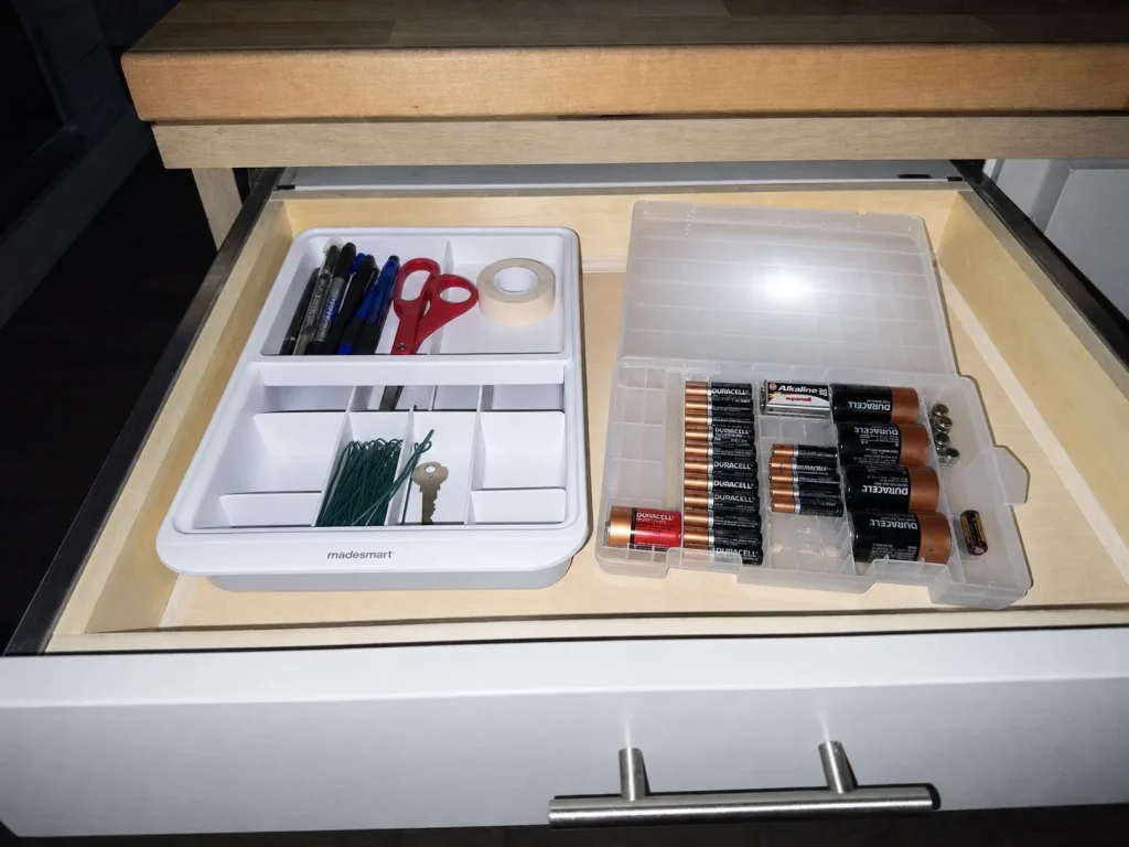 Junk drawer with a battery organizer case and a compartment tray holding separate categories