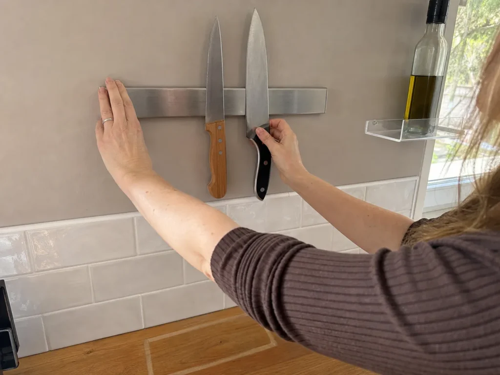 How to Organize Kitchen Counters That Stay Clear 7 Hands pressing a magnetic knife strip onto the wall to free kitchen counter space