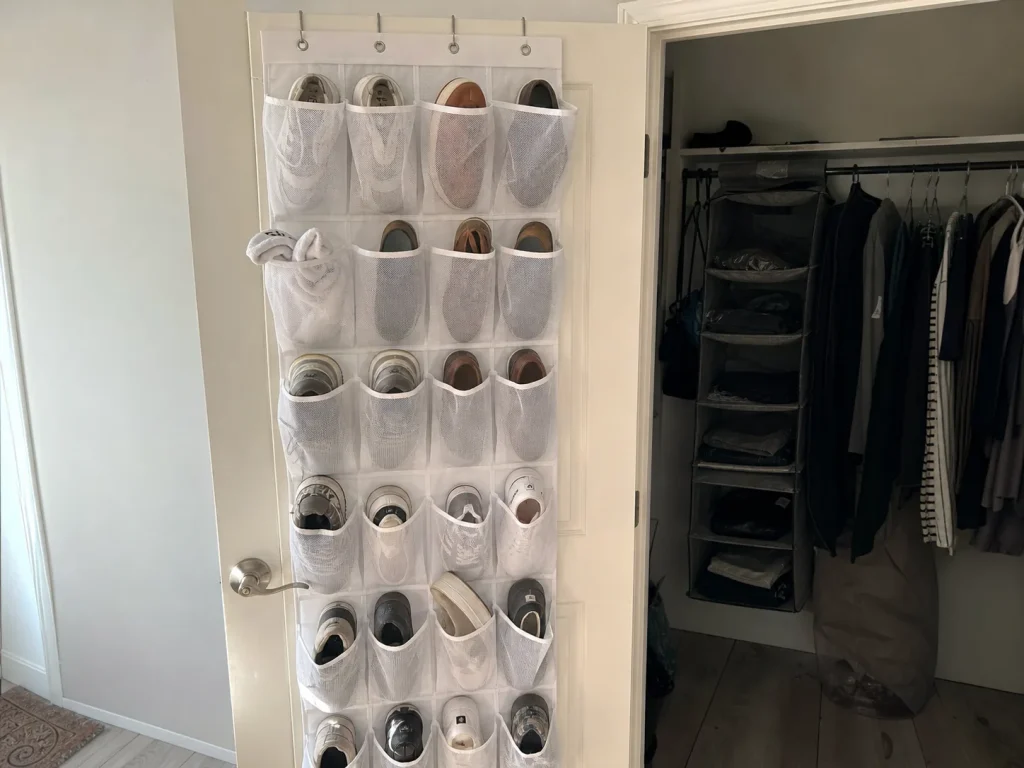 White over-the-door shoe organizer with mesh pockets hung on a closet door in a rental