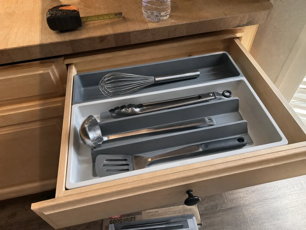 OXO expandable long tool organizer holding whisks and tongs flat in a kitchen drawer