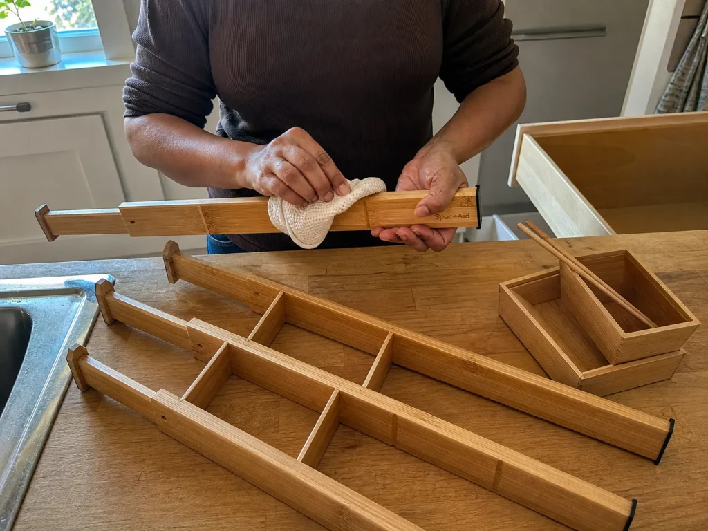 Best Kitchen Drawer Organizers That Hold Their Size 8 Hands drying a SpaceAid bamboo drawer divider with a towel beside an open kitchen drawer