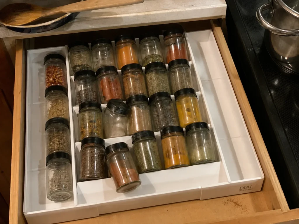 Best Kitchen Drawer Organizers That Hold Their Size 15 Dial Industries expandable spice tray holding jars on angled tiers inside a kitchen drawer