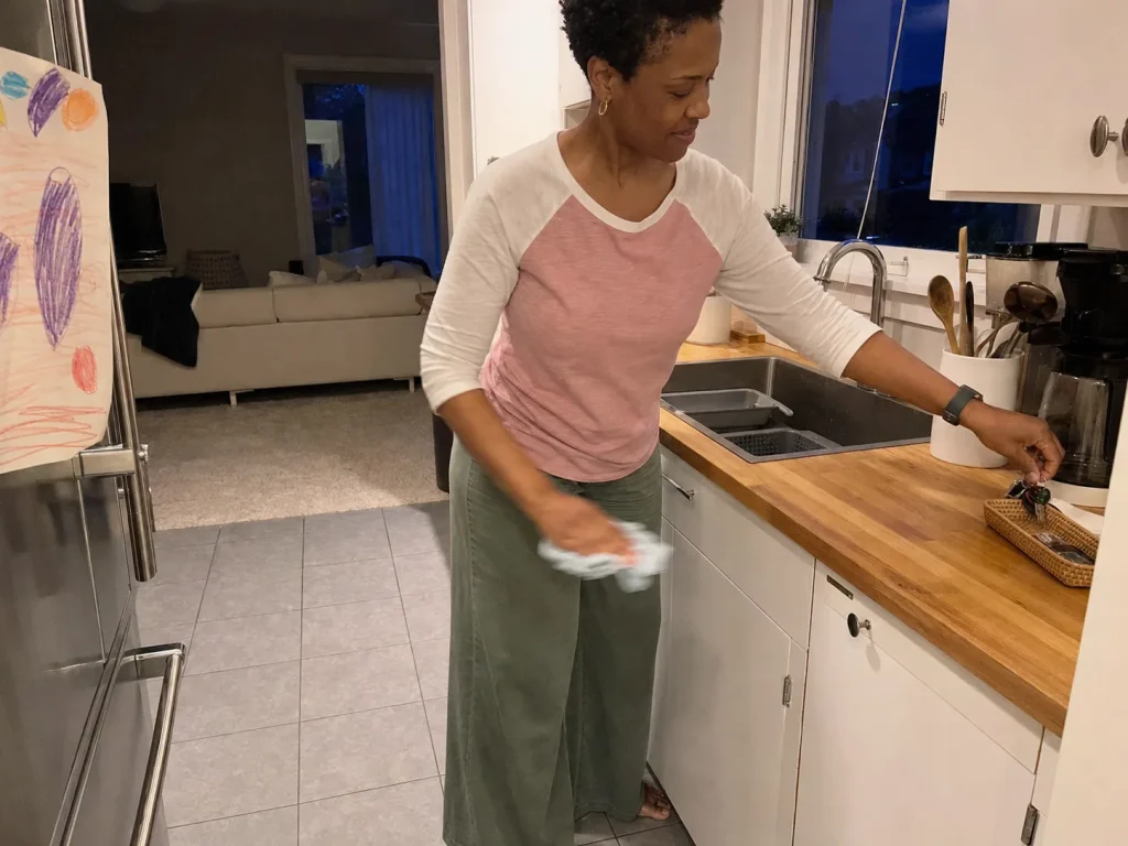 How to Declutter Kitchen Counters for Good 8 Woman doing a quick nightly counter reset, wiping the surface and returning drifted items