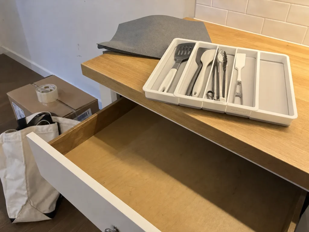 Best Kitchen Drawer Organizers That Hold Their Size 17 Utensil tray lifted out of a kitchen drawer showing a clean drawer floor with no adhesive marks