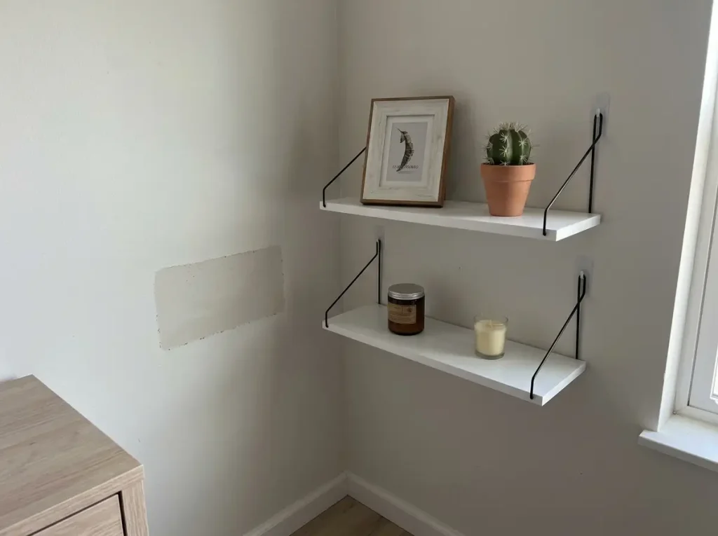 No-drill adhesive floating corner shelf holding only a plant and a small frame