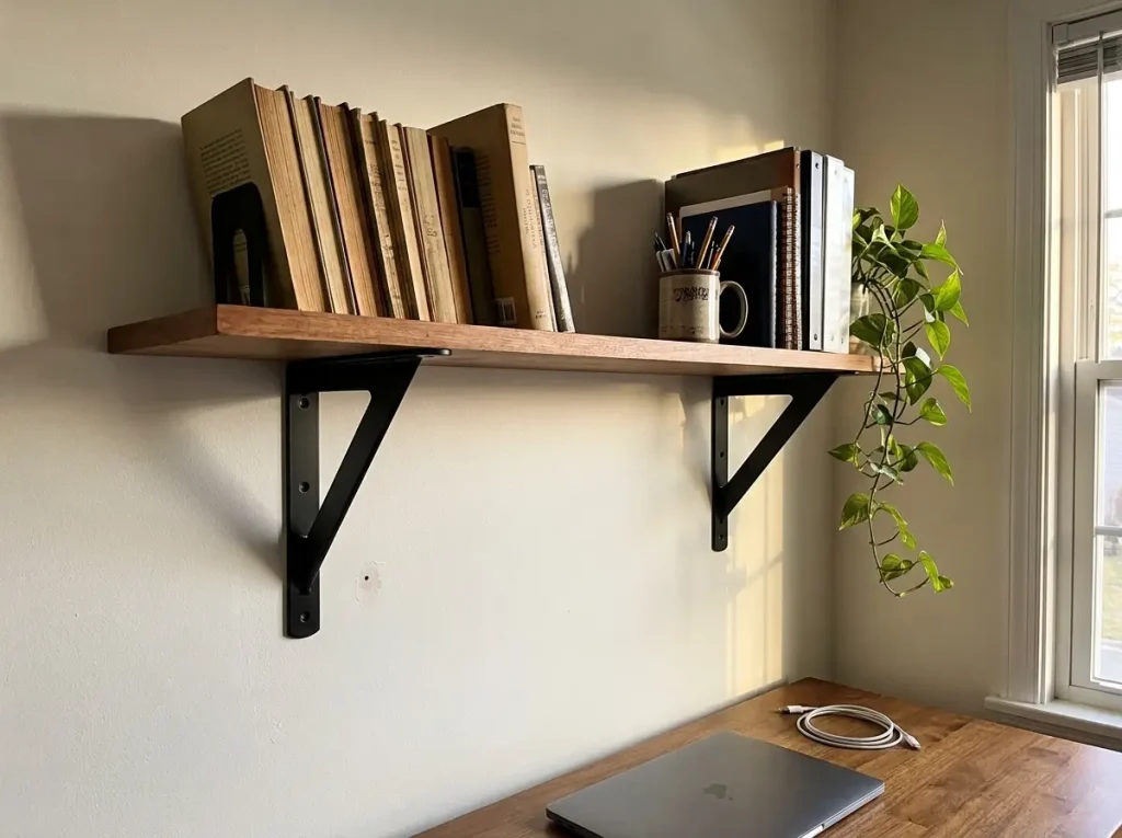 DIY wood shelf on black heavy-duty brackets mounted over studs in a home office
