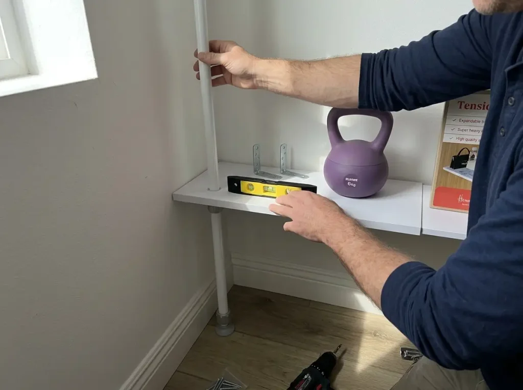 Hands adjusting a no-drill tension-rod corner shelving unit for a secure fit