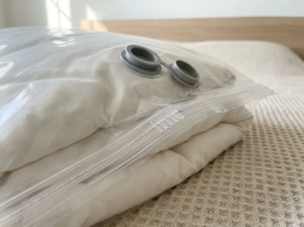 Close-up of a vacuum storage bag's one-way valve and double-zip seal on a folded duvet
