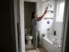 Best Shower Caddies for Renters and Shared Baths Woman setting up a hanging shower caddy on a fixed showerhead in a compact townhouse bathroom