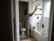 Best Shower Caddies for Renters and Shared Baths Woman setting up a hanging shower caddy on a fixed showerhead in a compact townhouse bathroom