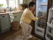 Fridge Organization for Meal Prep That Survives Wednesday Woman loading labeled glass meal prep containers into an organized fridge on Sunday afternoon
