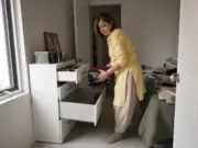 How to Organize Dresser Drawers That Stay Organized Woman sorting folded clothes into open dresser drawers during a bedroom drawer reorganization