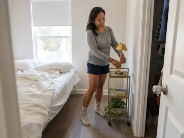 Small rental bedroom with a rolling cart used as a nightstand alternative beside the bed