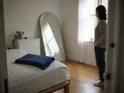 How to Make a Small Bedroom Look Bigger for Renters Small rental bedroom with a leaning arched mirror reflecting window light to make the room look bigger