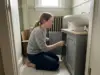 Under Sink Storage With a Pedestal Sink and No Cabinet Woman kneeling beside a pedestal sink with a wrap-around under sink storage cabinet in an older bathroom