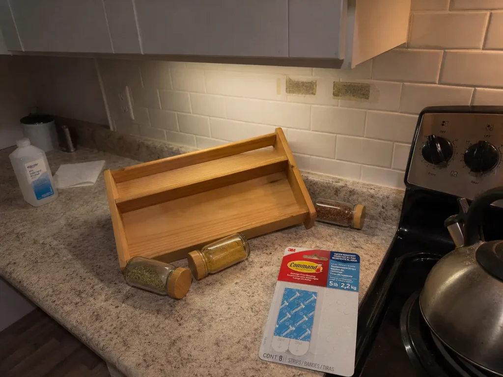 Adhesive strip residue on a kitchen wall where a DIY spice rack came loose above the range