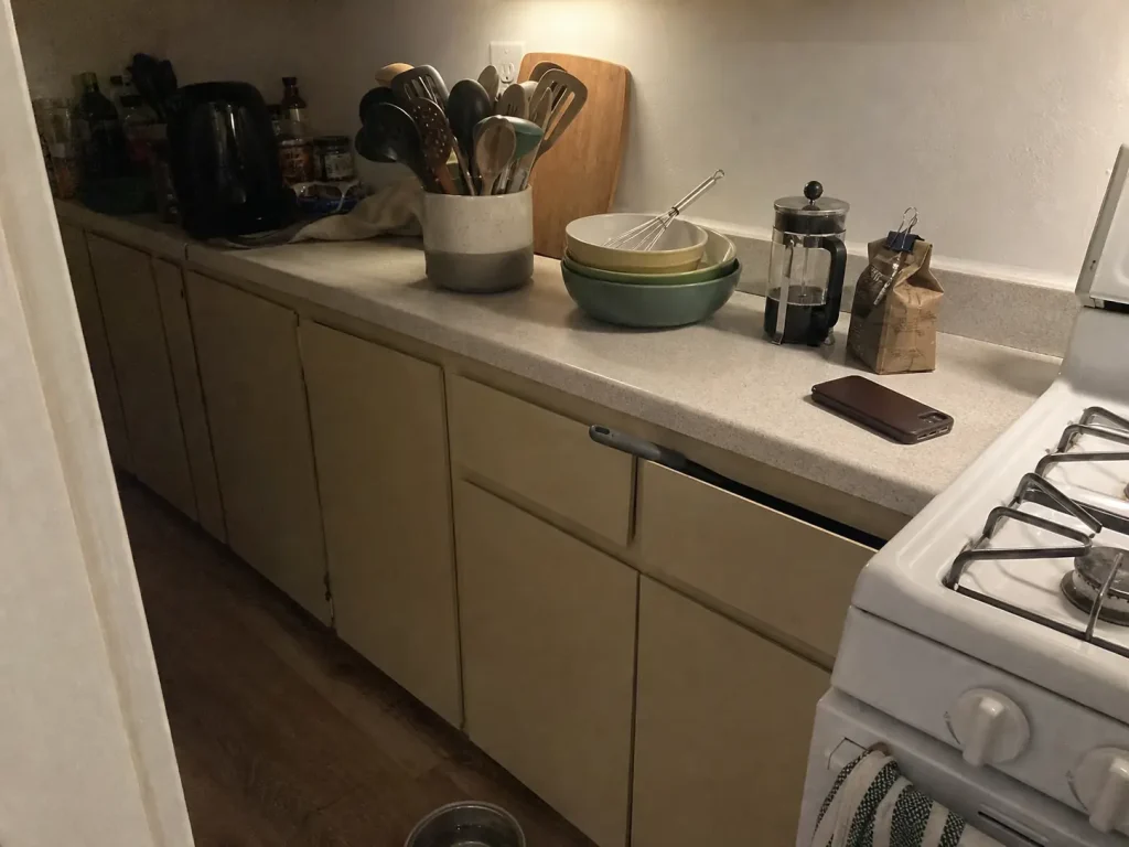 Why Your Small Kitchen With Few Drawers Stays Cluttered 1 Small kitchen counter with the same everyday tools piled beside the stove because the drawers are full