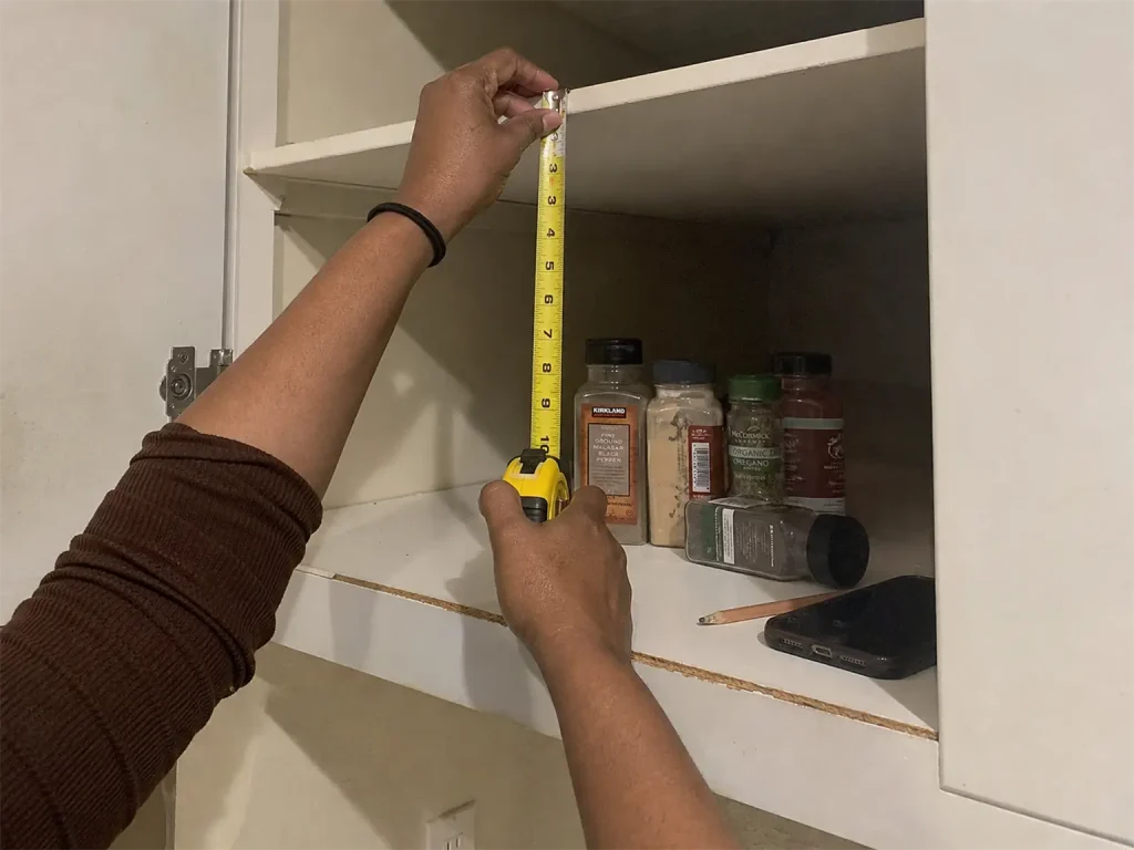 Best Spice Rack Organizers That Actually Stay Put 1 Hands measuring cabinet shelf height with a tape measure before buying a spice rack
