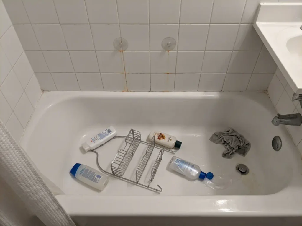 Fallen shower caddy and scattered bottles in a tub, showing why shower organization fails